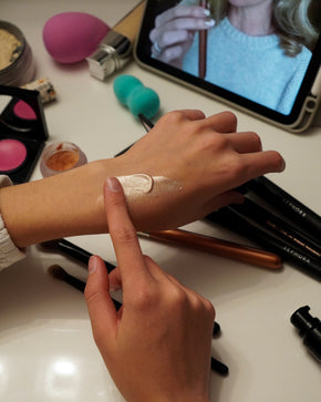 Person applying makeup on a vanity with various products during a beginner makeup step by step class